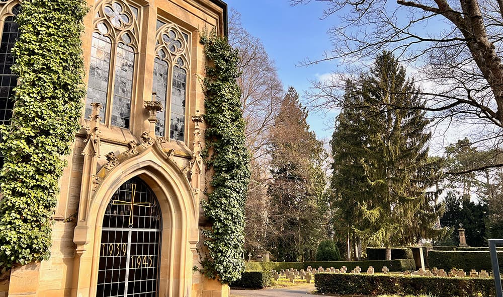 Bestattungsarten – Friedhofskapelle mit Grabsteinen und Blumenschmuck
